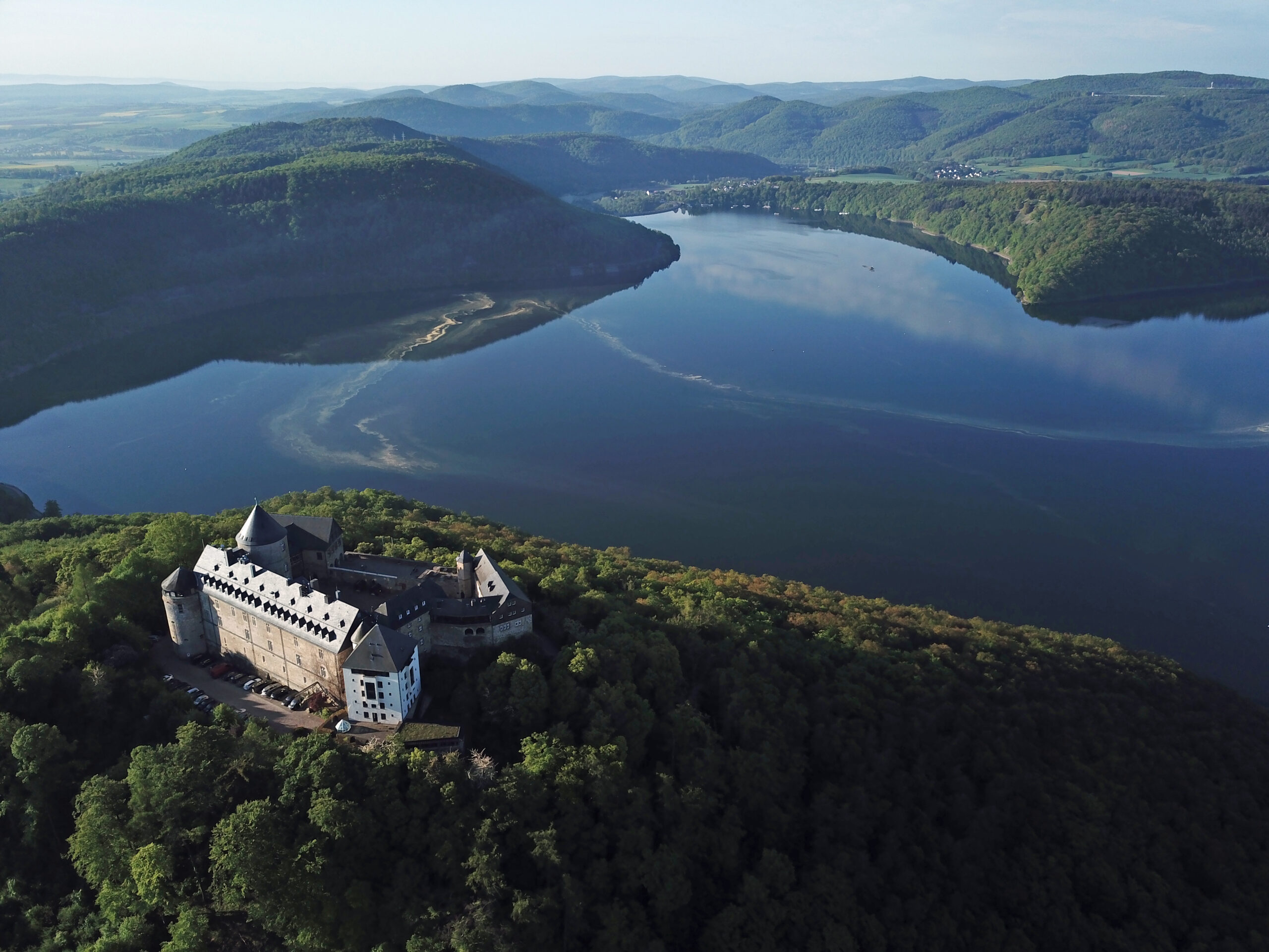 Blick über den Edersee & den Nationalpark Kellerwald-Edersee mit Schloss Waldeck im Vordergrund.